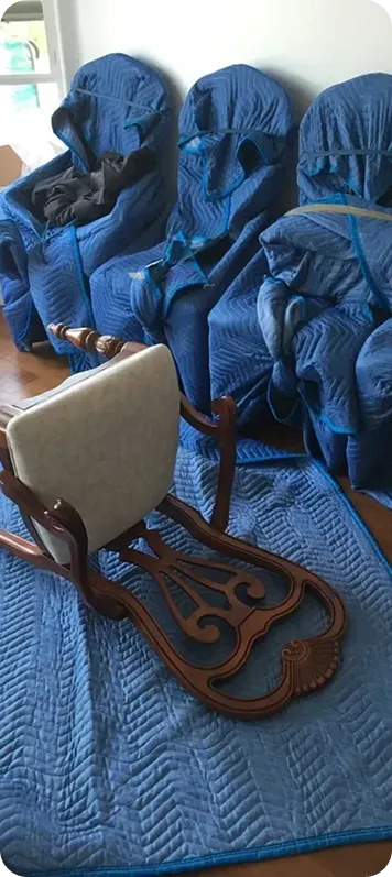 Dining chairs each wrapped in blue moving pads