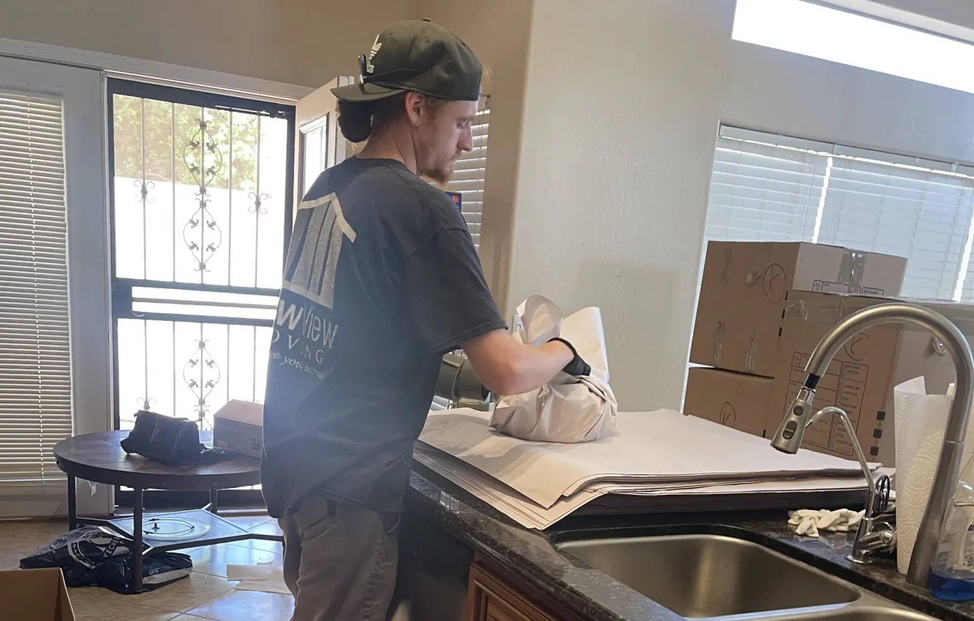 A NewView mover wraps dishes at a kitchen counter