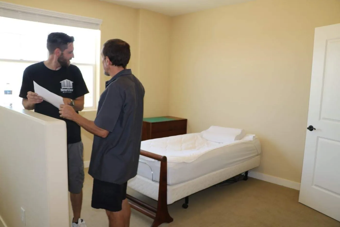 A NewView crew member reviews paperwork with a customer in an empty bedroom