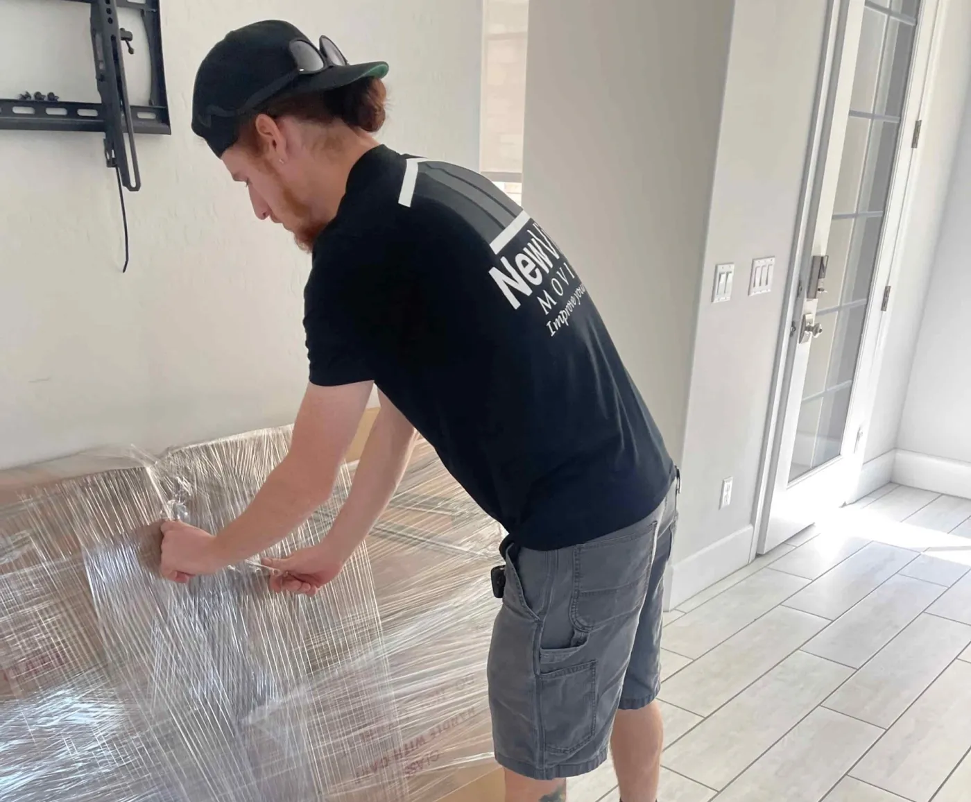 A NewView mover shrink-wraps a piece of furniture in an empty room
